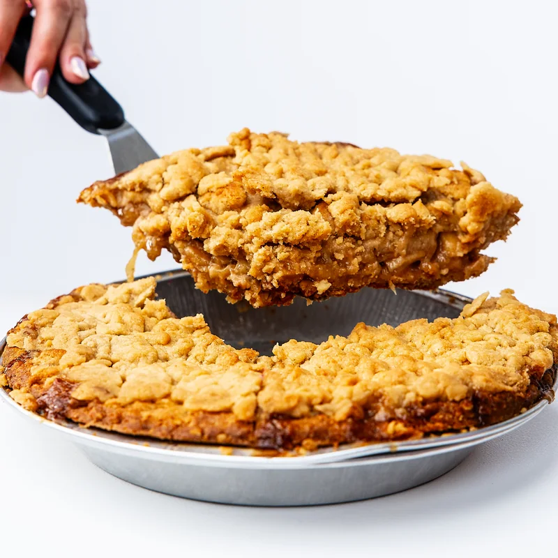 A generous crumb-topped pie slice lifted from its pan