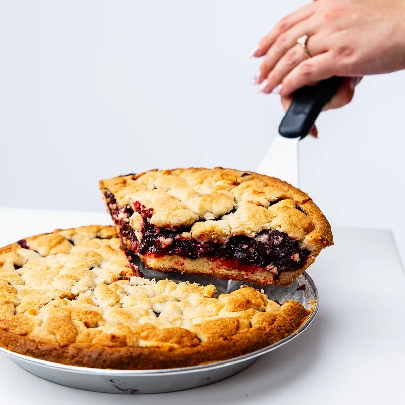 A thick dark-fruit pie slice with a golden cookie crust